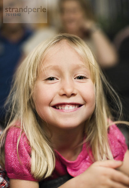 Porträt eines fröhlichen kleinen Mädchens auf der Vorderseite mit Eltern im Hintergrund