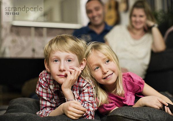 Porträt eines kleinen Jungen  der mit seiner Schwester vor dem Fernseher liegt.