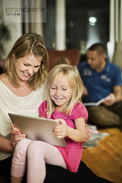 Glückliches Mädchen mit digitalem Tablett und Mutter zu Hause