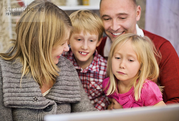 Glückliche vierköpfige Familie mit Laptop zu Hause