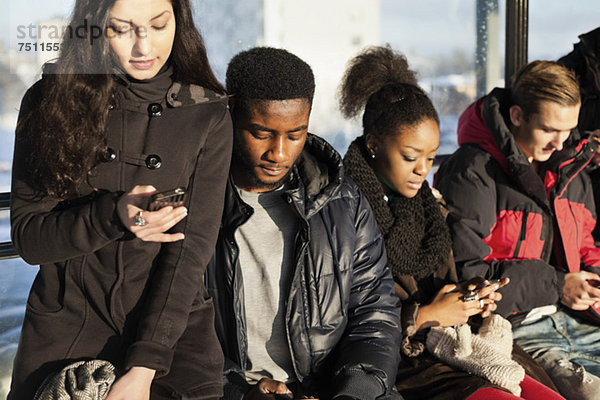 Gruppe multiethnischer Freunde  die Mobiltelefone benutzen