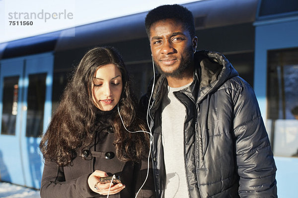 Junge Freunde beim Musikhören durch Freisprecheinrichtung gegen den Zug