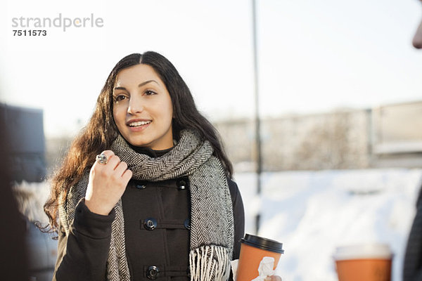 Fröhliche junge Frau in Winterkleidung mit männlichen Freunden