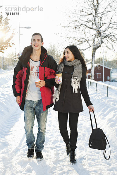 Junge Freunde  die auf einer verschneiten Straße spazieren gehen.