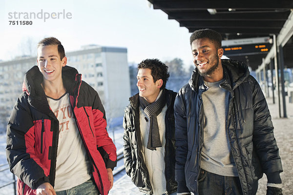 Fröhliche multiethnische Freunde  die auf dem Bahnsteig spazieren gehen