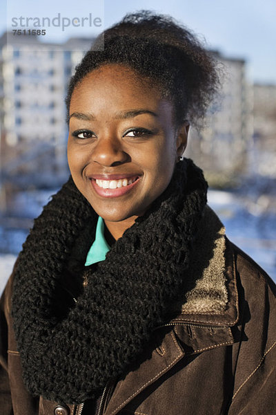 Porträt einer fröhlichen jungen Afroamerikanerin  die im Freien lächelt.