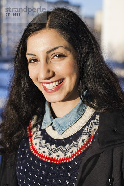 Porträt einer fröhlichen jungen Frau aus dem Nahen Osten  die im Freien lächelt.
