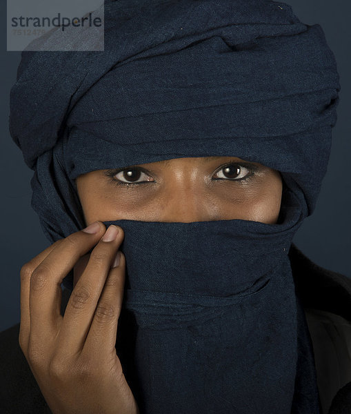 Tuaregmädchen  Targia  verschleiert mit Chech  Gesicht geheimnisvoll verhüllt mit Hand  Portrait  Algerien  Nordafrika