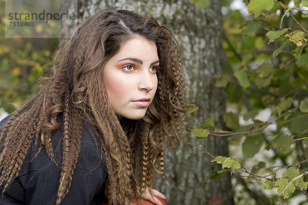 Junge Frau mit langen Haaren vor einem Baum  Portrait
