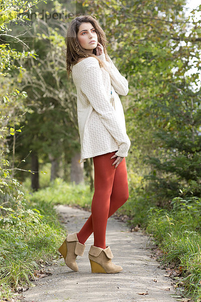Junge Frau mit langem weißem Pullover und roter Strumpfhose  Outdoor