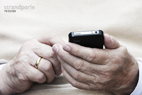 Senior hält Smartphone in der Hand