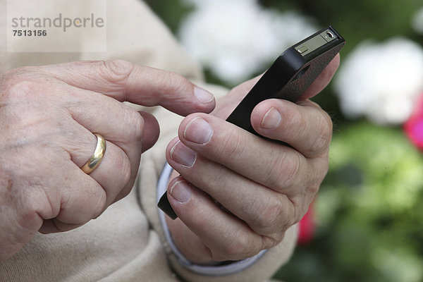 Senior hält Smartphone in der Hand