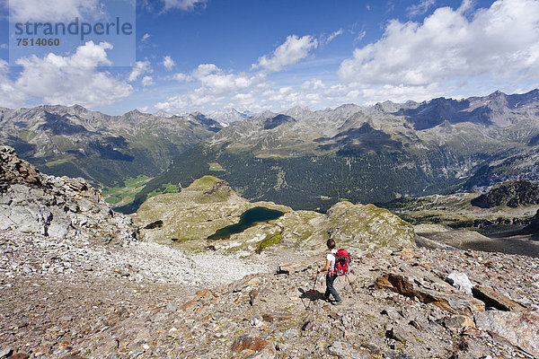 Bergsteiger beim Abstieg vom Schneebiger Nock in der Rieserfernergruppe im Pustertal  unten der große Malersee  Südtirol  Italien  Europa