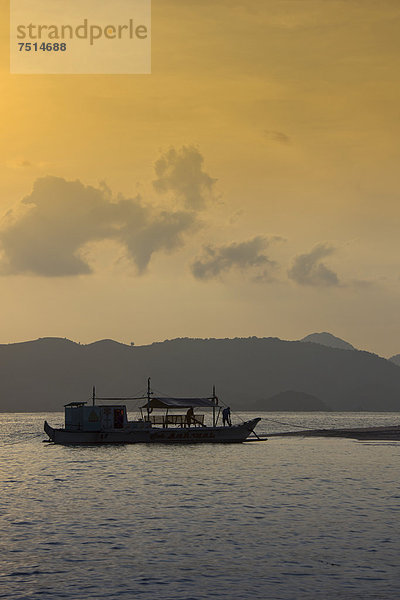 Eine Banka  traditionelles philippinisches Auslegerboot liegt im Abendlicht am Strand vor Anker  Busuanga  Philippinen  Asien