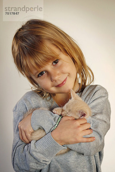 Mädchen  7 Jahre  schmust mit Babykatze  Portrait
