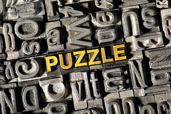 'Alte Bleilettern bilden das Wort ''PUZZLE'''