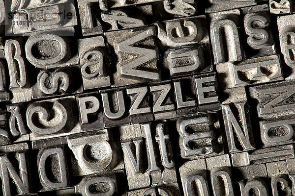 'Alte Bleilettern bilden das englische Wort ''PUZZLE'''