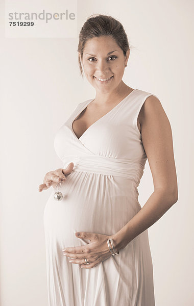Schwangere Frau hält eine Mini-Discokugel vor ihren Bauch