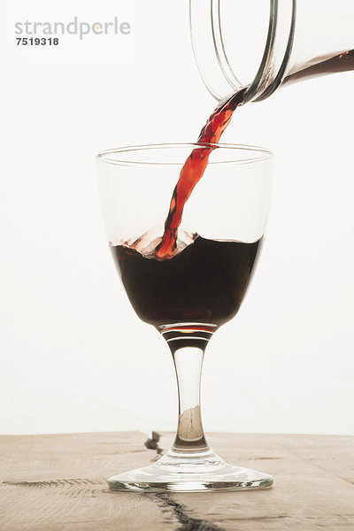 Ein Glas wird mit Rotwein aus einer Karaffe gefüllt