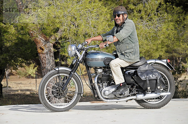 Älterer Mann fährt auf einer Triumph Tiger 500 cc  Baujahr 1956  englisches Motorrad  Altea  Costa Blanca  Spanien  Europa  ÖffentlicherGrund