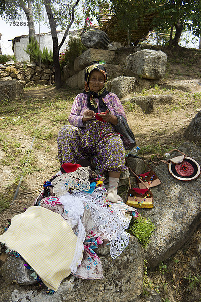 Eine alte Frau mit Lesebrille verkauft Stickereien an Touristen  Bafa Gölü  Bafasee  oder auch «amiÁi Gölü  Binnensee  Westküste der Türkei  Bafasee  Kapikiri  Mus  Türkei  Asien