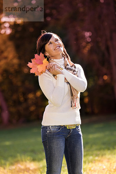 stehend junge Frau junge Frauen halten Herbst Laub