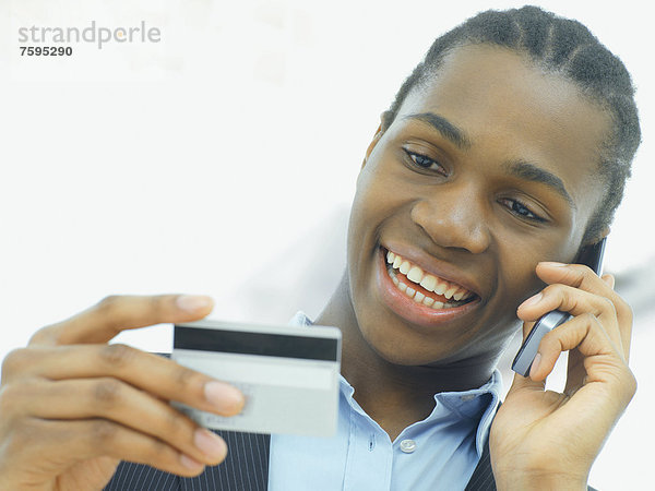 Geschäftsmann  afroamerikanisch  telefoniert  mit Kreditkarte
