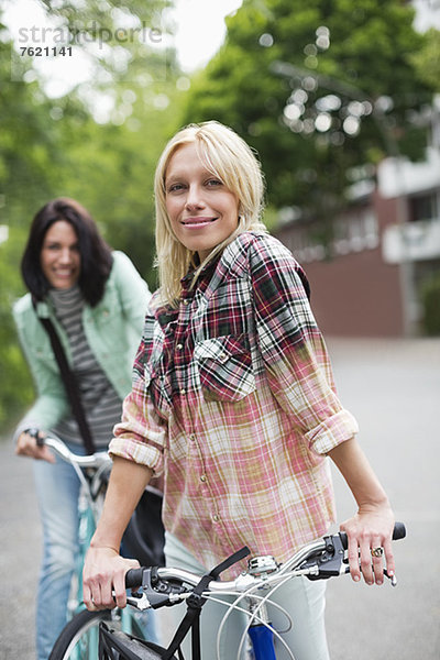 Frauen stehen auf Fahrrädern auf der Stadtstraße