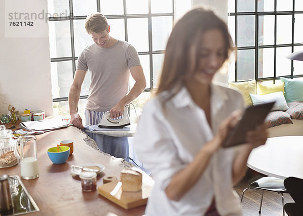 Frau mit digitalem Tablett als Freundesbügeleisen in der Küche