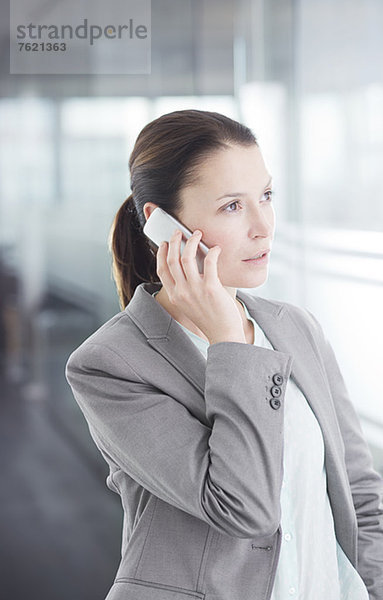 Geschäftsfrau beim Telefonieren im Büroflur