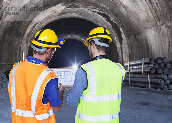 Arbeiter lesen Blaupausen im Tunnel