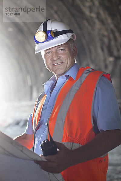 Geschäftsmann liest Blaupausen im Tunnel