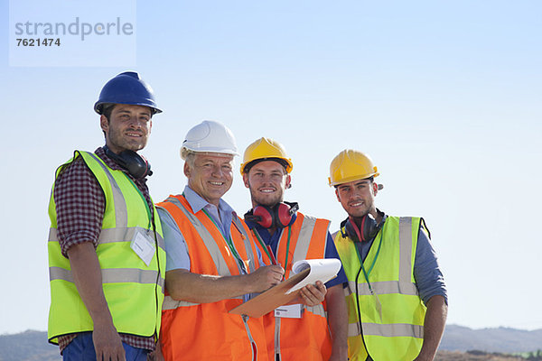 Geschäftsmann und Arbeiter lächeln vor Ort