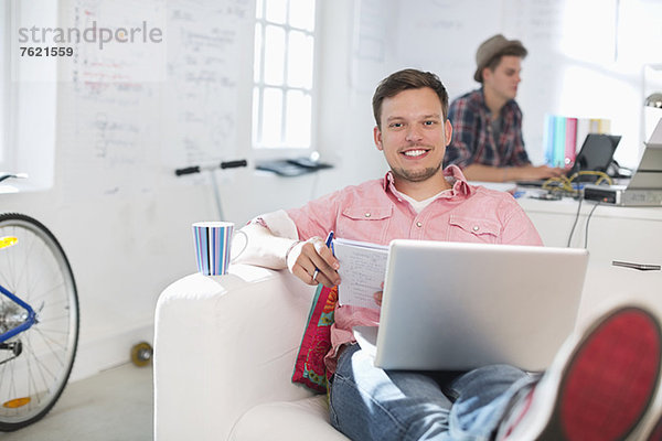 Geschäftsmann mit Laptop auf Sofa im Büro