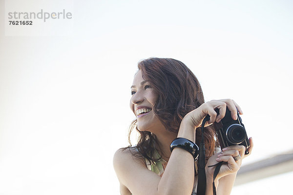Lächelnde Frau beim Fotografieren im Freien