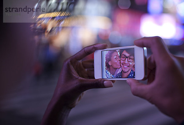 Frau hält Handy mit Foto auf dem Bildschirm