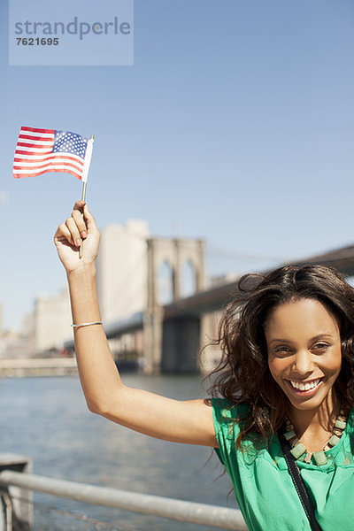 Frau winkt mit amerikanischer Flagge an der Hafenpromenade