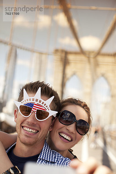 Paar in neuartiger Sonnenbrille fotografiert auf urbaner Brücke