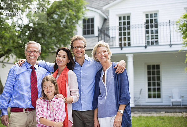 Familie lächelt gemeinsam vor dem Haus