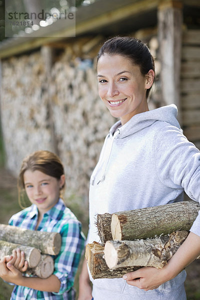 Mutter und Tochter mit Brennholz im Freien