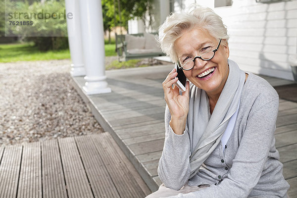 Frau spricht auf dem Handy auf der Veranda