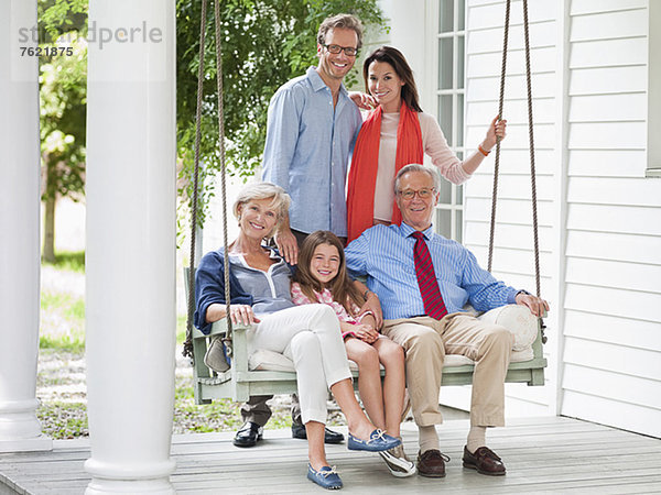 Familie lächelt gemeinsam auf der Veranda