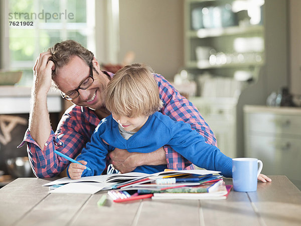 Vater und Sohn machen Hausaufgaben am Küchentisch