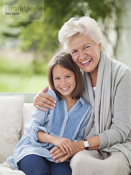 Frau und Enkelin lächelnd auf der Veranda-Schaukel
