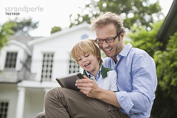 Vater und Sohn nutzen das digitale Tablett im Freien