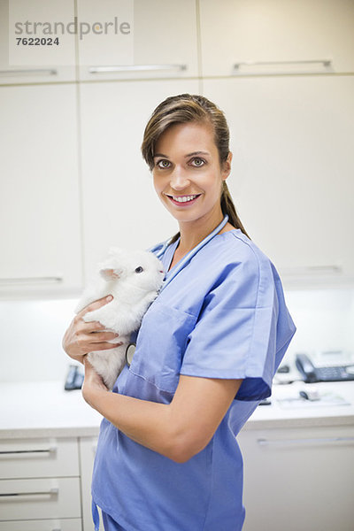 Lächelnder Tierarzt mit Kaninchen in der Tierarztpraxis