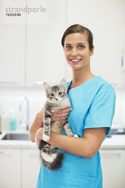 Lächelnder Tierarzt hält Katze in Tierarztpraxis