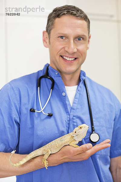 Lächelnder Tierarzt mit Eidechse in der Tierarztpraxis