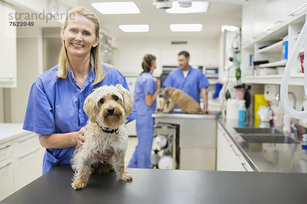 Tierarzt lächelt mit Hund in der Tierarztpraxis