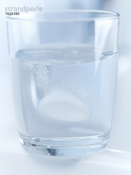 Nahaufnahme der Pille zischend im Glas Wasser